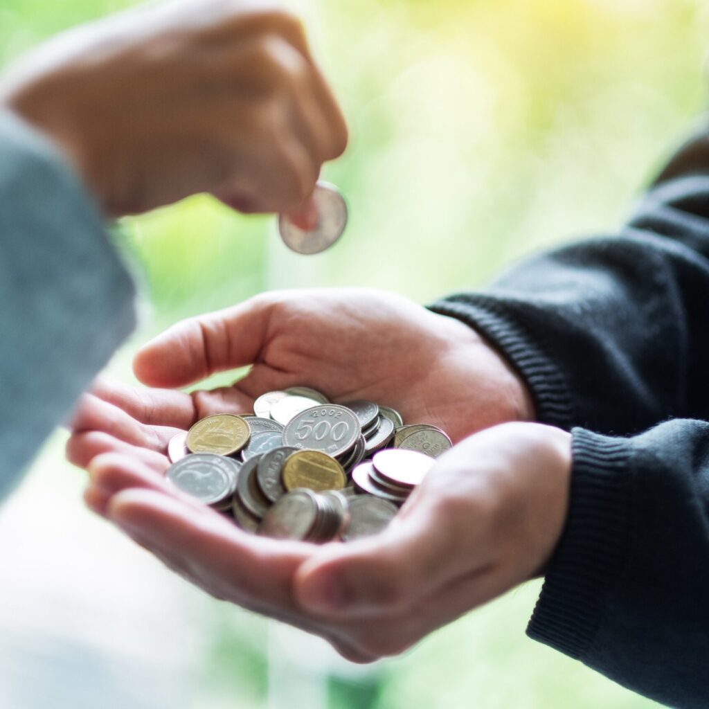 Closeup Image Of A Hand Putting Coins Into Another ZF32UUR Scaled 1 1024x1024