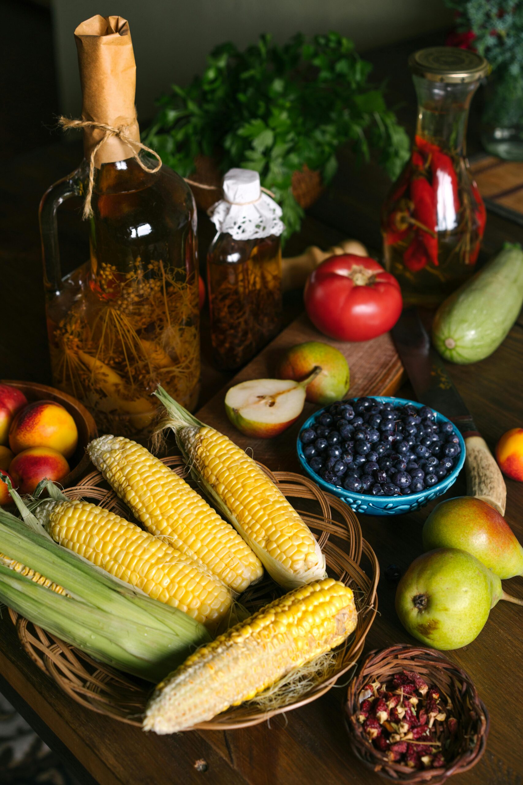 Vibrant assortment of fresh fruits and vegetables including corn, blueberries, and tomatoes on a wooden table.